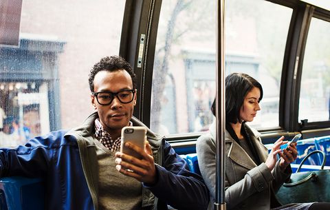 Man and woman on bus using smartphones