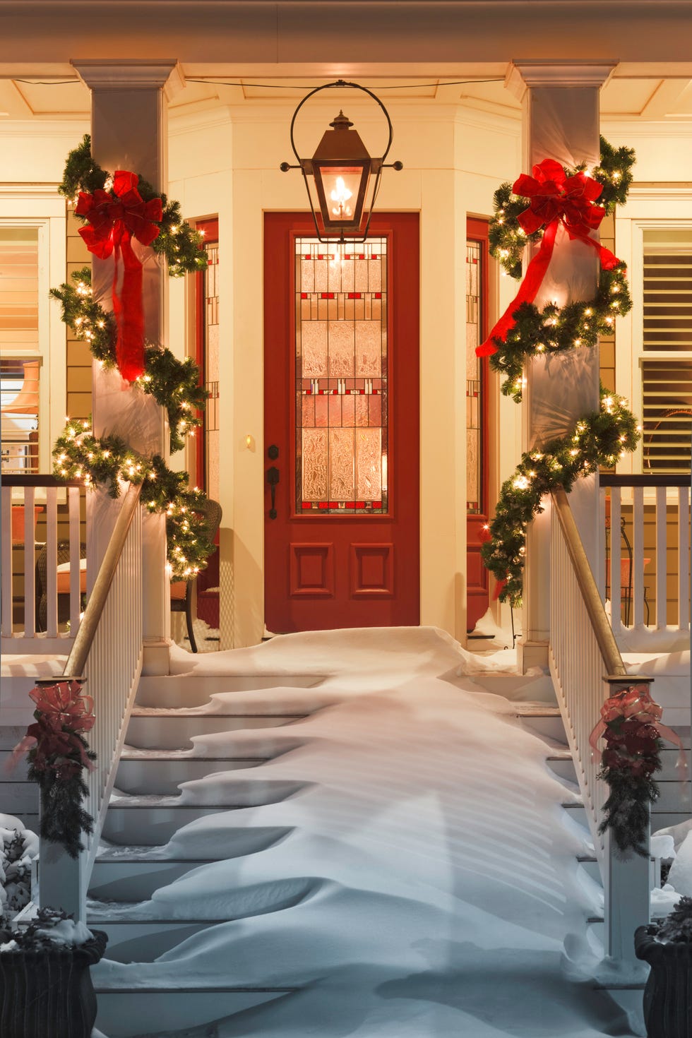 inviting christmas doorway with snow on porch stairs and railing