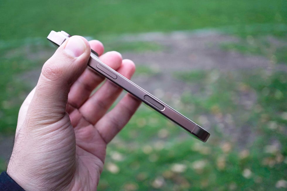a person holding a smartphone from the side showcasing its buttons and design