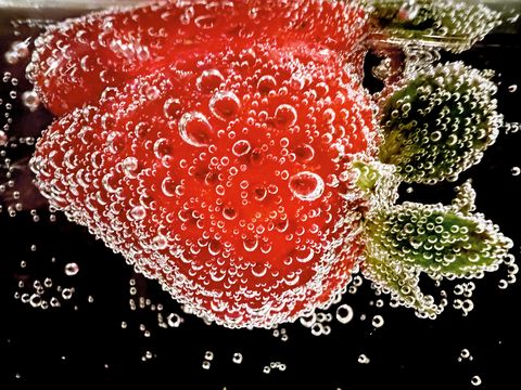 a strawberry submerged in carbonated drink