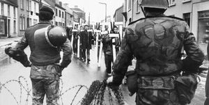 demonstrators in dungiven, northern ireland, march past british troops on february 6, 1972, to lay crosses on the steps of the local royal ulster constabulary headquarters, in memory of the 13 residents of londonderry aka derry who were killed by british troops on bloody sunday one week earlier