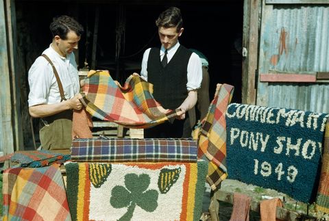 Een wever links laat zijn handgemaakte stof zien in zijn winkel in Clifden Hij gebruikte mos om de wol groen te kleuren en de schil van uien om hem bruin te kleuren volgens een artikel uit 1951 in de National Geographic