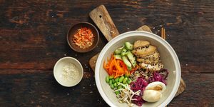 iron rich foods, vegan poke bowl aka tofu poke bowl with tender tofu, red cabbage, carrot, avocado, edamame and bean sprout on a bed of brown rice flat lay top down composition on dark wooden background horizontal image with copy space