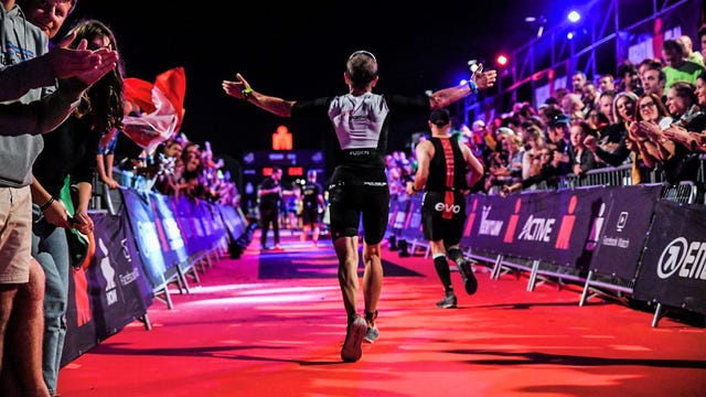 un competidor abre los brazos llegando a la meta del ironman de barcelona