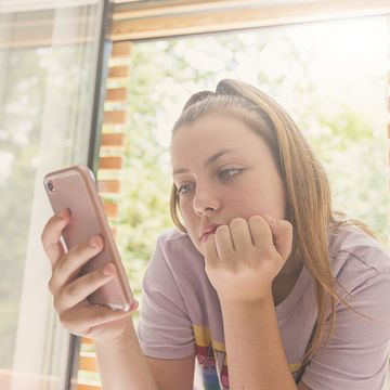 teenage girl using smartphone in bedroom