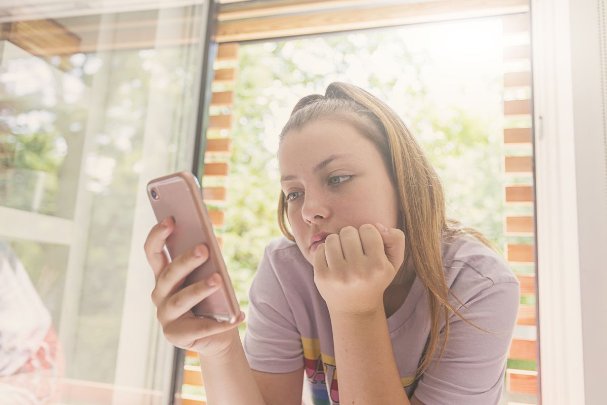 teenage girl using smartphone in bedroom