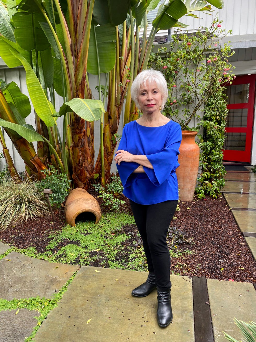la escritora, de 79 años, posa con un blusón azul y pantalón negro