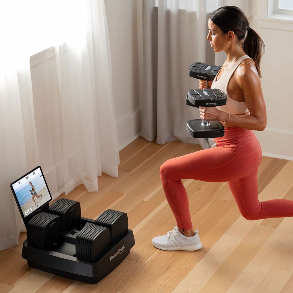 woman lunging with iselect dumbbells while watching ifit workout on tablet