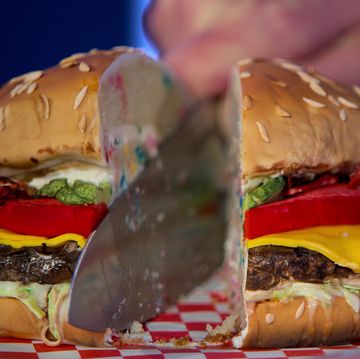 hyperrealistic cake meant to look like a cheeseburger being cut in half with a knife