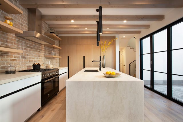 cocina abierta con isla central y pared de ladrillo visto