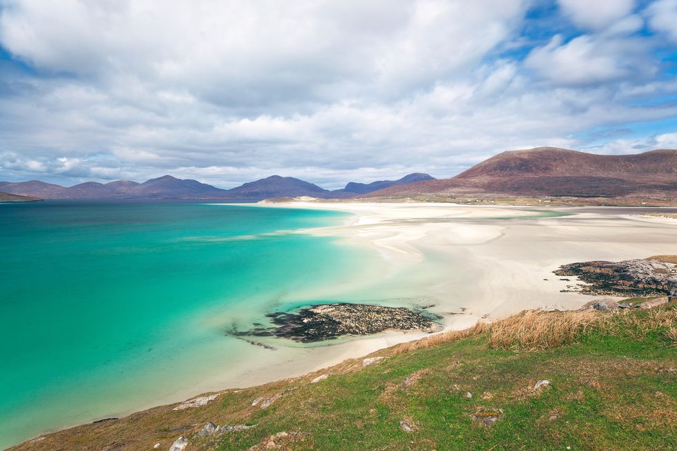seilebost beach in the foreground with luskentyre beach beyond this area is windswept and cold, but the colour of the water is like the caribbean