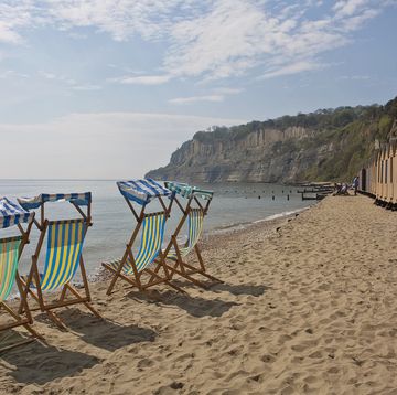 deck chairs line the beach next to the beach huts on the right at shanklin in the isle of wight