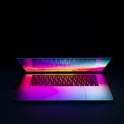 isolated high tech open laptop with abstract vibrant color screen on a dark background