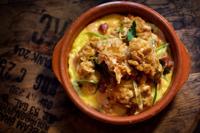 close up of chinese chicken salad with crispy wonton strips and scallions served in a terra cotta bowl over creamy dressing.