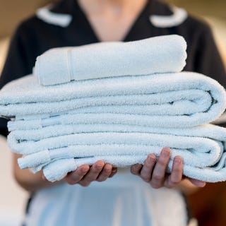 close up of unrecognizable housekeeper holding towels at a hotel