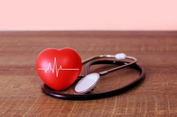 stethoscope and heart examination red on old wooden floor health care concept