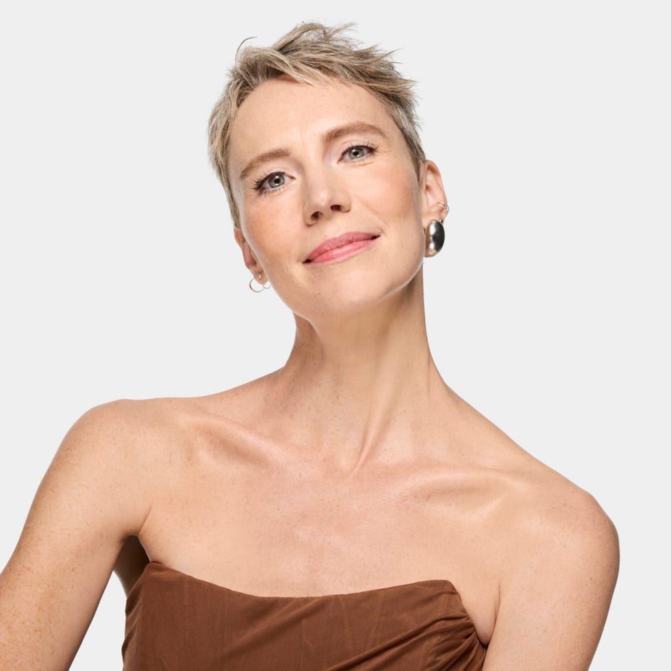 a glowing model wearing a brown strapless top with large earrings