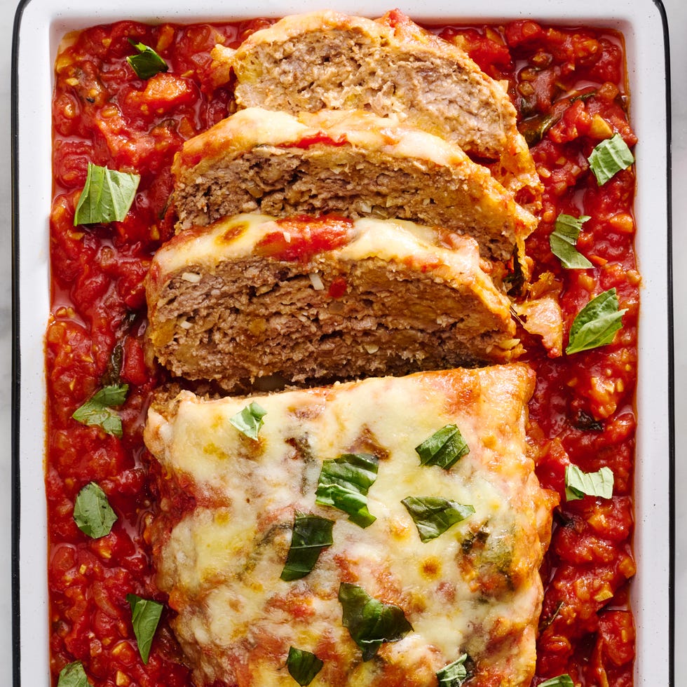 meatloaf covered in cheese and parsley surrounded by red sauce