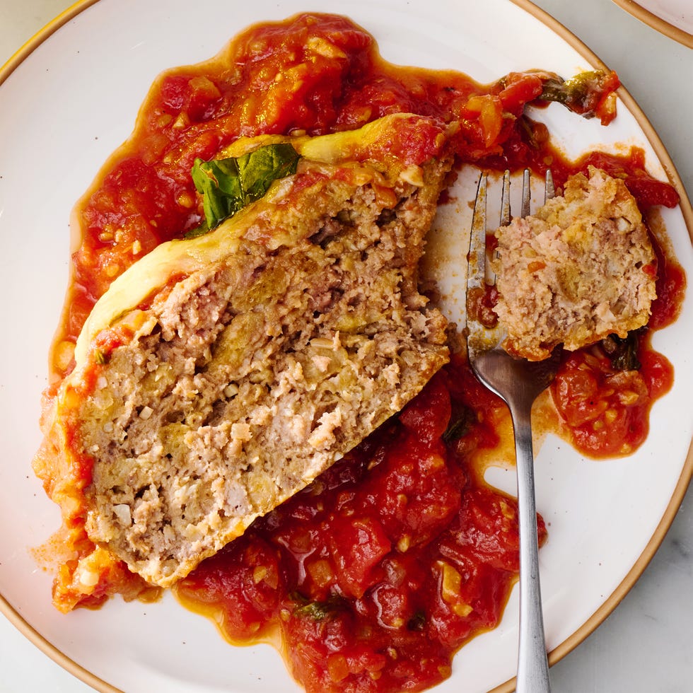 meatloaf covered in cheese and parsley surrounded by red sauce