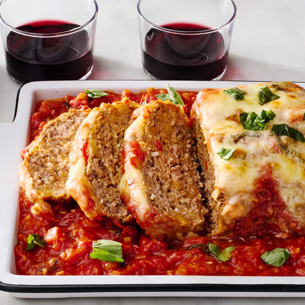 meatloaf covered in cheese and parsley surrounded by red sauce