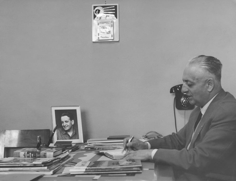 enzo ferrari writing at a desk with a portrait of his son nearby