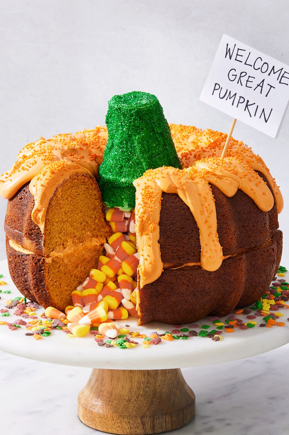 two pumpkin bundt cakes stacked on each other, filled with candy corn, and decorated to look like a pumpkin