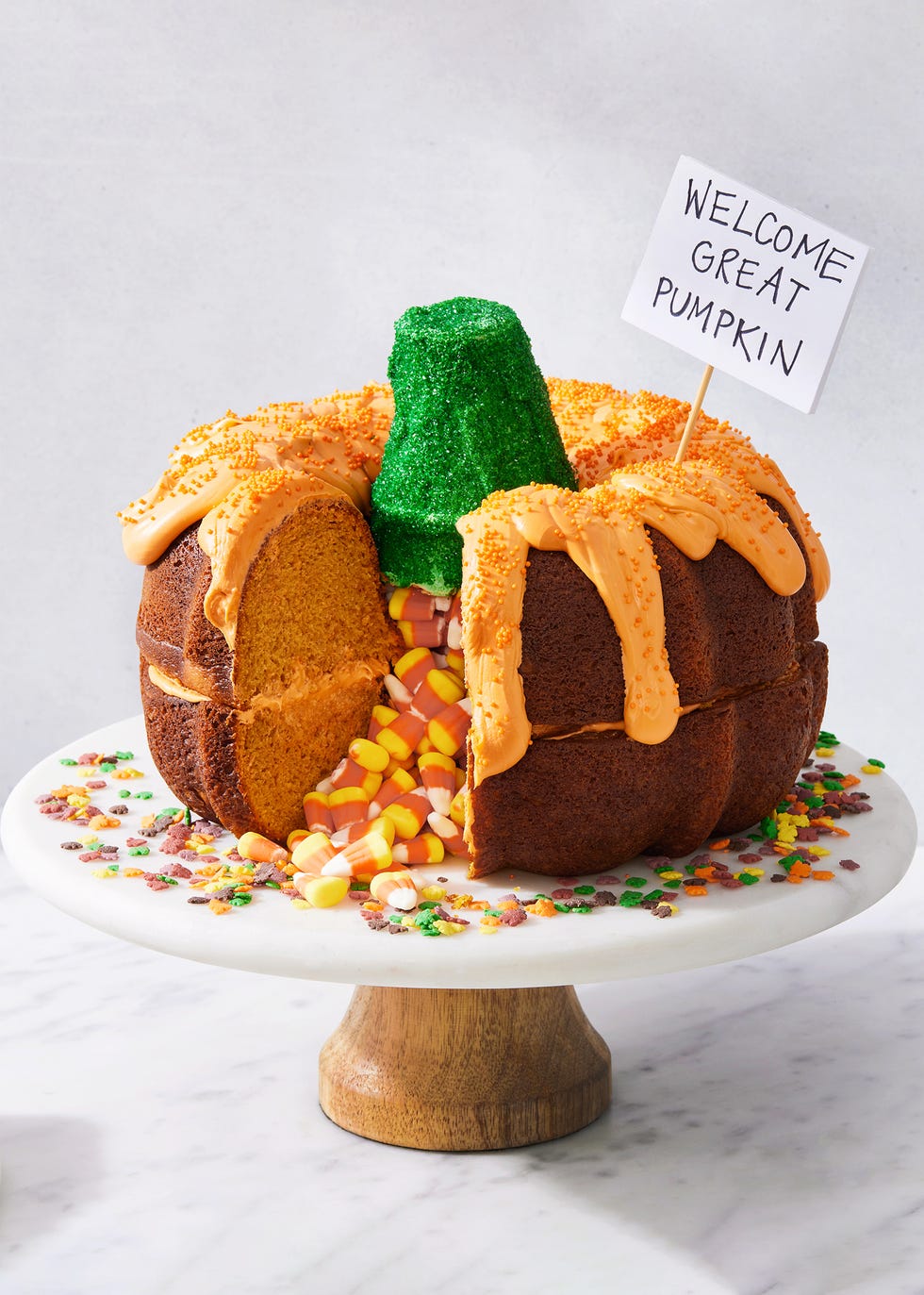 two pumpkin bundt cakes stacked on each other, filled with candy corn, and decorated to look like a pumpkin