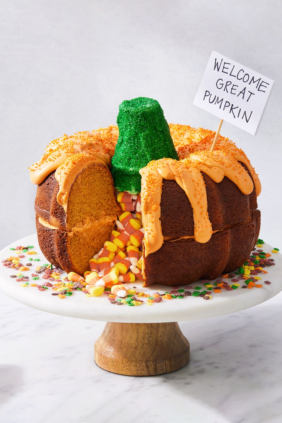 two pumpkin bundt cakes stacked on each other, filled with candy corn, and decorated to look like a pumpkin