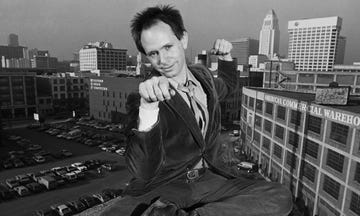 a man sitting on a ledge with his hands up in the air