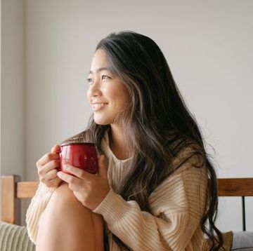 jonge vrouw zit op bed met kop thee