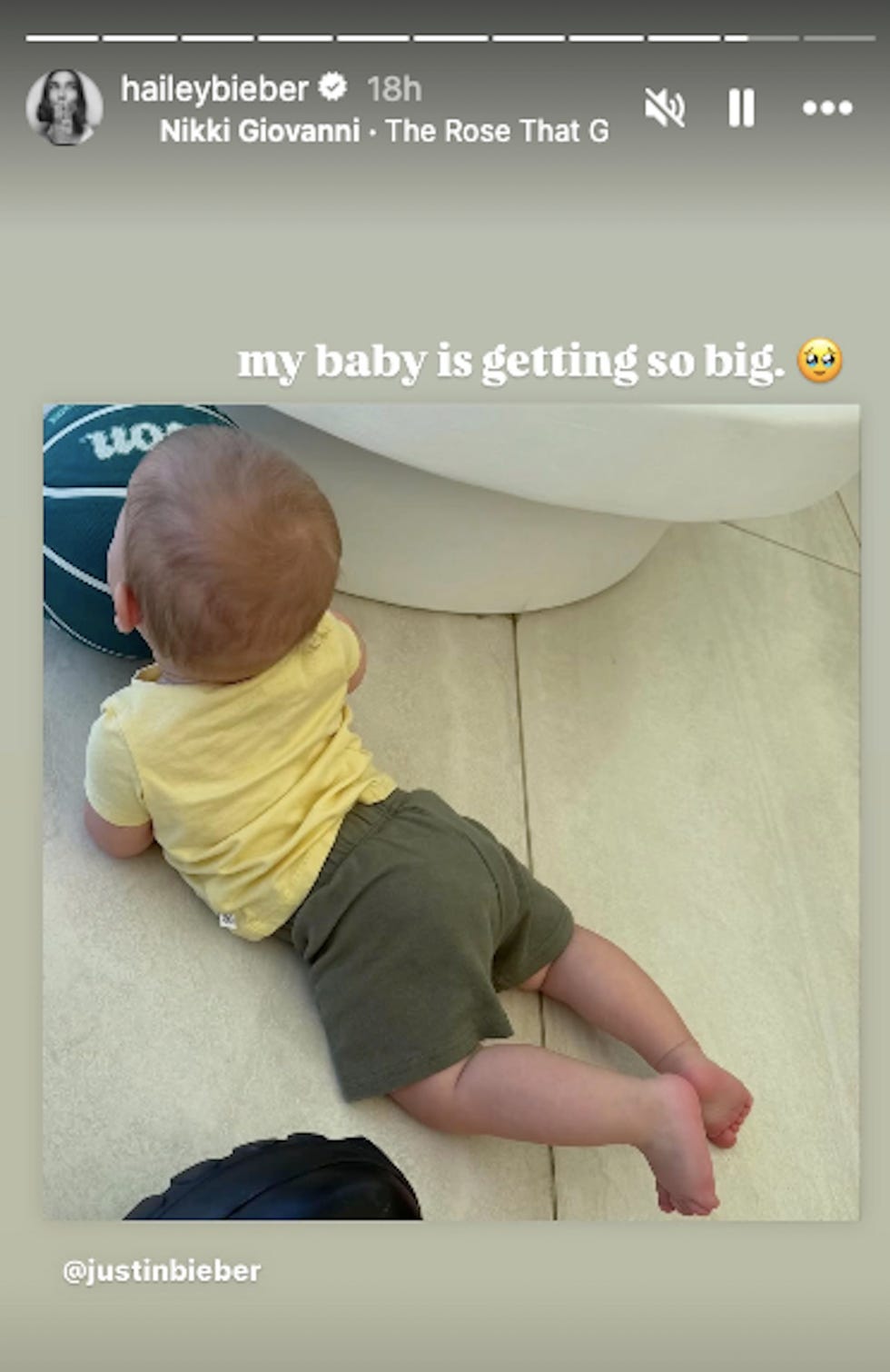 a baby crawling on a tiled floor near a basketball