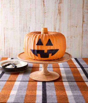 jack o' lantern shaped cake with orange frosting on a cake stand