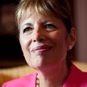 jackie speier wearing a black shirt, pink suit jacket, a white necklace and staring just off to the side of the camera