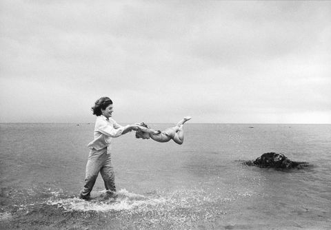 Jackie swings Caroline in the shallows at Hyannis Port, 1959