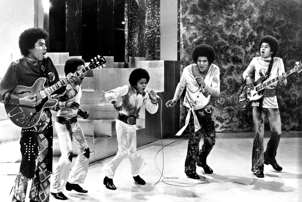 tito jackson, marlon jackson, michael jackson, jackie jackson, and jermaine jackson of the jackson 5 sing and dance on stage during a performance, tito and jermaine are playing guitar and michael is holding and singing into a microphone