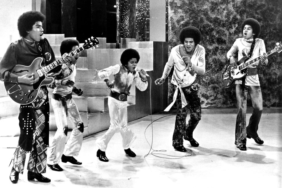 tito jackson, marlon jackson, michael jackson, jackie jackson, and jermaine jackson of the jackson 5 sing and dance on stage during a performance, tito and jermaine are playing guitar and michael is holding and singing into a microphone