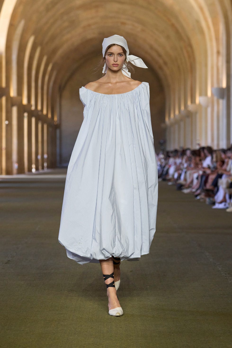 Catwalk photo of a model in a white dress during the Jacquemus Show