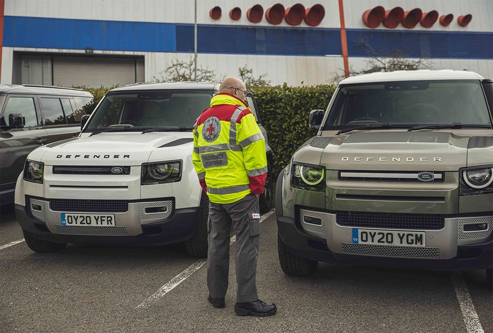 Operario de Cruz Roja observando coches Land Rover