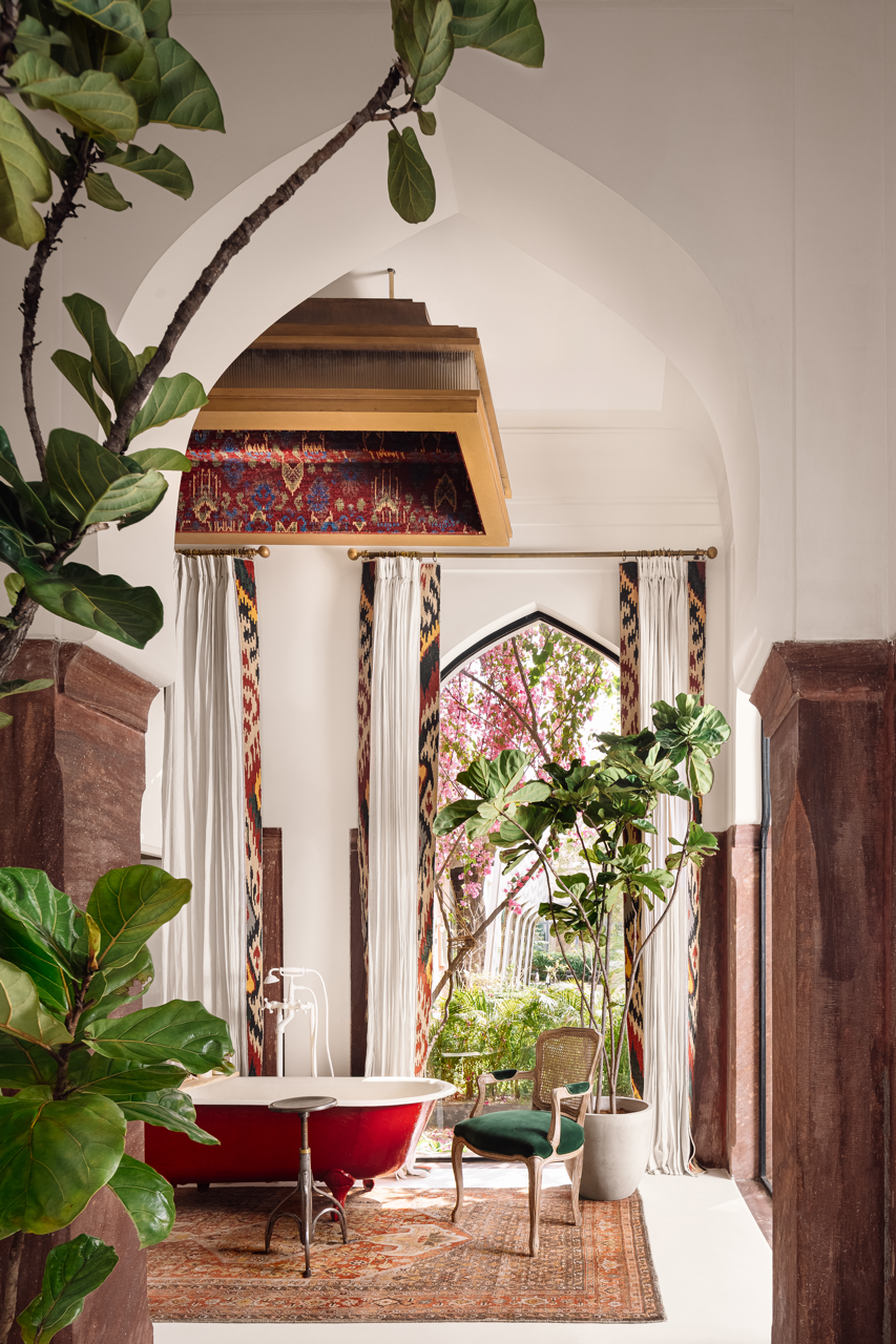 bathroom with a vintage red bathtub and lush green plants