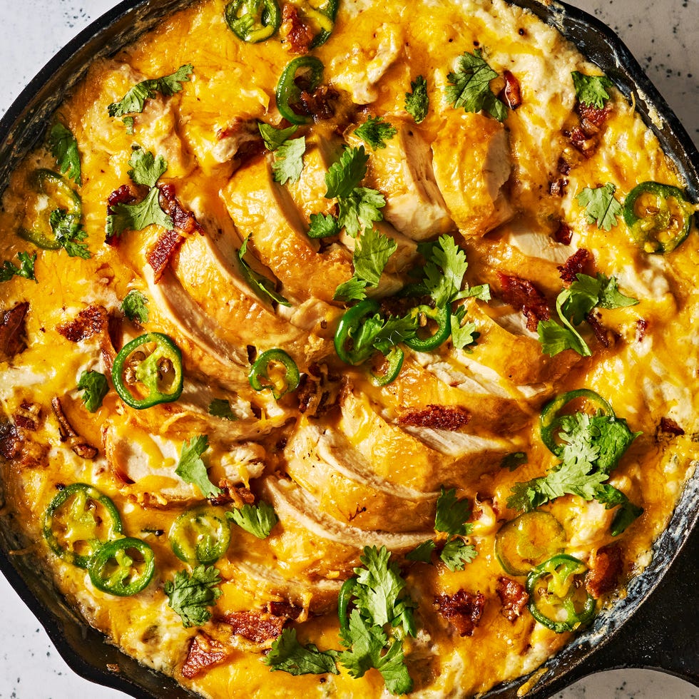 chicken in a skillet covered in cheese with jalapeños