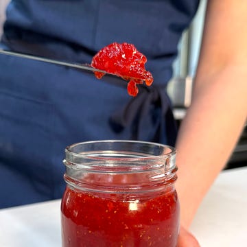 person holding a scoop of jam above a jar of jam person holding a scoop of jam above a jar of jam