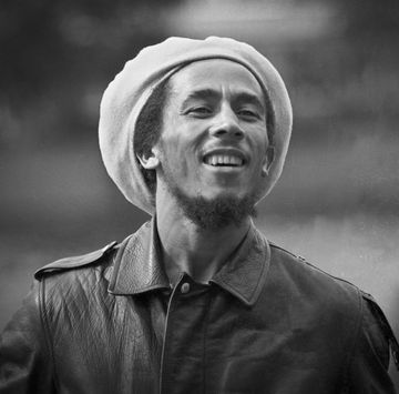 bob marley wearing a leather coat and hat and smiling for a photograph