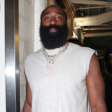 james harden looks at the camera with a straight face, he wears a white sleeveless shirt and a large multistrand diamond necklace