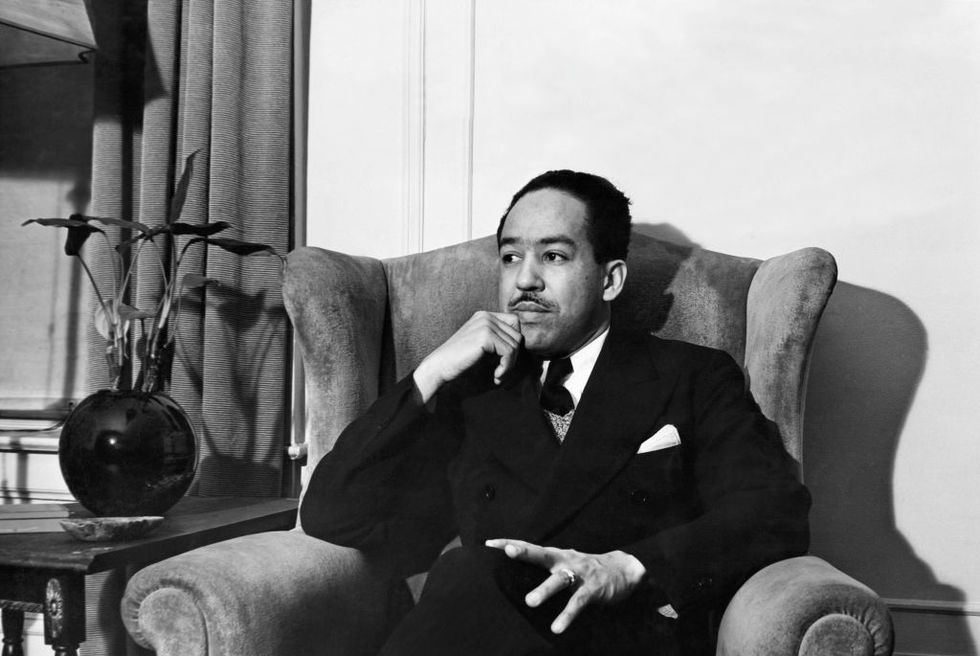 langston hughes sits in chair with legs crossed