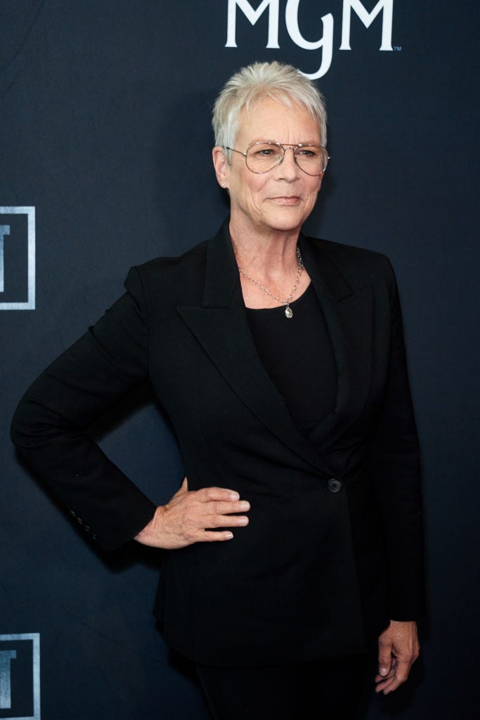 jamie lee curtis with her right hand on her hip as she smiles for a photograph at an event