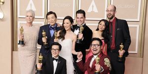 first row shows ke huy quan and daniel kwan kneel holding oscars second row shows jamie lee curtis, james hong, michelle yeoh, jonathan wang, stephanie hsu, and daniel scheinert stand while holding oscars