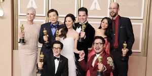 first row shows ke huy quan and daniel kwan kneel holding oscars second row shows jamie lee curtis, james hong, michelle yeoh, jonathan wang, stephanie hsu, and daniel scheinert stand while holding oscars