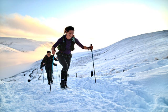 hikers ascending a snowy trail in a mountainous landscape