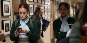 madelaine petsch in a green school uniform looking at her phone unhappily