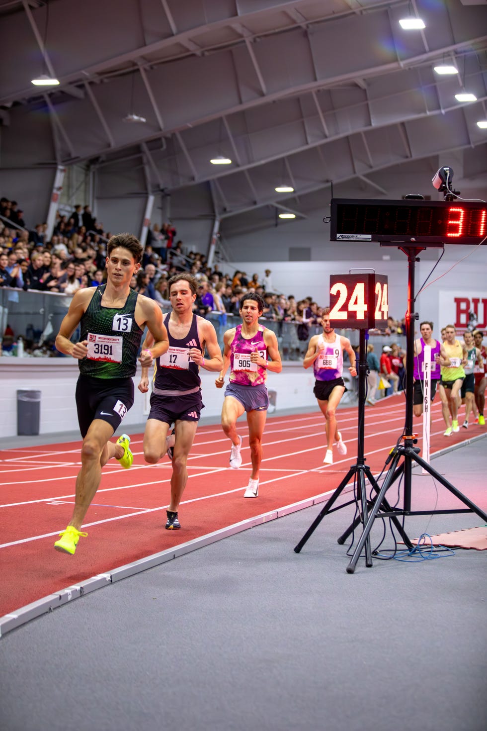 athletes competing in a track race indoors with a digital timer